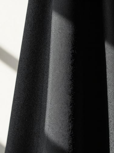Extreme close-up of a high-fashion charcoal fabric drape under dramatic directional window light, showing millimeter precision stitching, minimalist composition, 35mm lens.