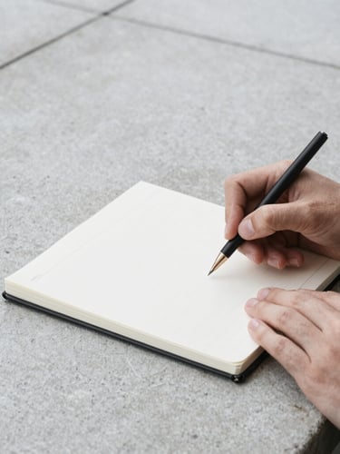 Tight crop on hands reviewing a notebook on a concrete desk, abstract architectural details, desaturated cool tones, crisp environmental photography, high contrast.