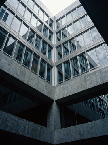 Architectural low-key photography of modern corporate headquarters interior, concrete and glass structures, cool silver light filtering through windows, high contrast, 35mm lens