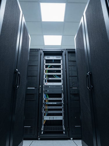 Precise overhead wide shot of a cloud infrastructure rack room, clean white overhead strobes illuminating cable management panels and blank-face servers, no people, cool clinical lighting, geometric symmetry