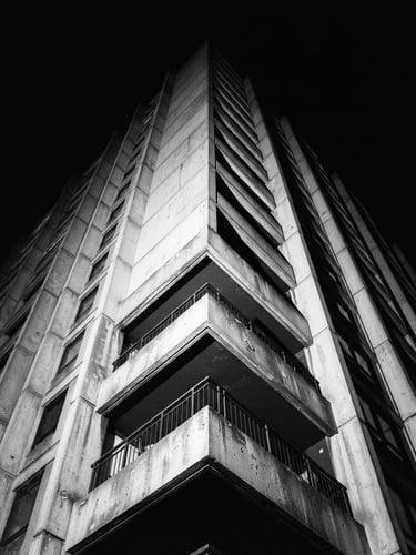 Stark black and white architectural angle of a concrete London building, harsh direct flash, deep shadows, high contrast, 35mm