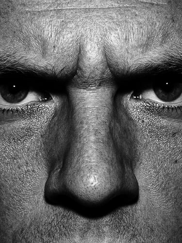 Extreme close-up of intense, serious human eyes staring directly into the lens, harsh direct flash, high contrast black and white photography, gritty editorial, 35mm