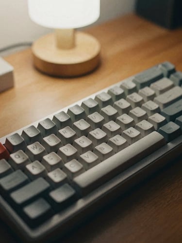 A close-up of a vintage mechanical keyboard on a wooden desk, soft warm desk-lamp light, muted desaturated tones, 35mm film grain.