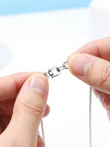 Macro shot of a quality control inspector examining a silver necklace clasp, bright studio lighting, white background, 50mm lens