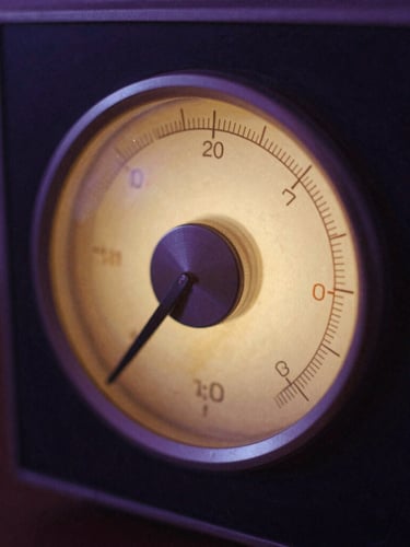 Macro detail of a vintage analog radio dial glowing with soft amber light in a dark violet room, atmospheric film photography.