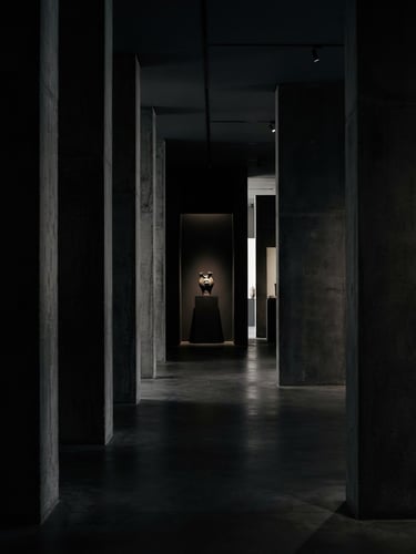 Dramatic low-key architectural interior, sharp concrete columns framing a pristine minimalist space, high-contrast shadows, 35mm lens photography.