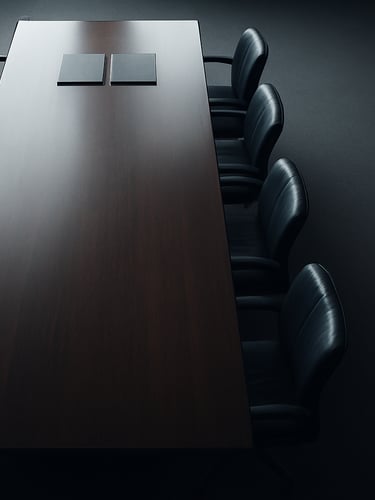 Wide panoramic view from above of an empty institutional boardroom table, overhead flat-lay framing, cool north-facing daylight, dark polished surface reflecting faint document folders at the far edge, generous negative space to the right