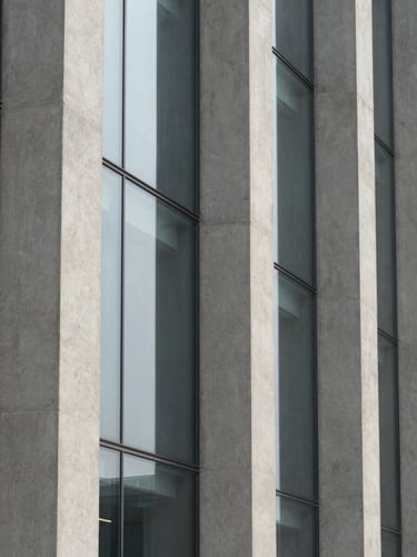 Abstract close-up of structural concrete columns and glass panels, sharp morning shadows, minimalist architectural photography