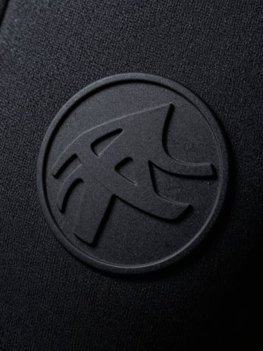 Macro close-up of a high-relief matte black silicone print on heavy charcoal cotton fabric, dramatic side lighting emphasizing texture and depth, 35mm photography