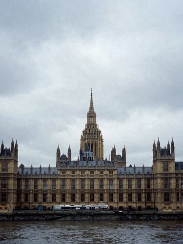 Wide photojournalistic shot of the Palace of Westminster under heavy overcast British skies, moody cool-toned shadows, 35mm gritty documentary style.