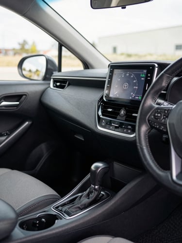 Close-up of a Toyota Corolla interior dashboard and centre console, natural window light, clean upholstery visible, odometer showing 87000 km on digital cluster, no people
