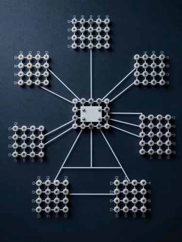Overhead view of a precise technical network topology diagram on a dark navy surface, clean white connector lines linking labeled node clusters, cool studio light flattening all detail, minimal shadow, institutional schematic aesthetic