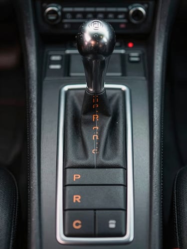 Straight-on, eye-level technical close-up of a vintage Porsche gated shifter console, clean metal gates, orange shift pattern lettering, moody low-key garage lighting
