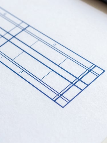 Overhead macro shot of a clean technical diagram on a desk, sharp focus, crisp white paper with navy blue structural lines, bright cool daylight