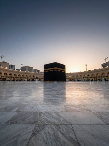 Wide panoramic view from a rooftop terrace looking toward the Masjid al-Haram at dawn, the Kaaba a small illuminated form at the distant center, vast open marble courtyard stretching forward, soft pre-sunrise light diffusing across the stone, no figures present, deep navy sky fading to warm ivory at the horizon