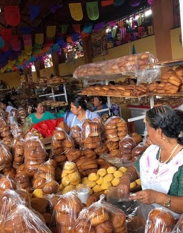 Un puesto de panadería tradicional mexicana en un mercado, repleto de pan dulce fresco y panes dulce