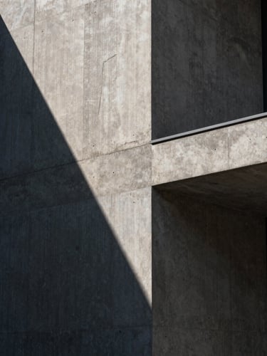 Tight abstract architectural crop of a modern concrete and dark marble building facade, dramatic directional sunlight casting deep diagonal shadows, high contrast, minimalist editorial style.