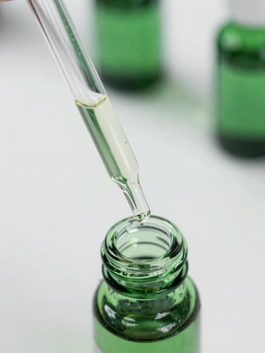 Macro close-up of a sterile laboratory glass pipette dispensing clear botanical oil into a green glass vial, sharp focus, bright clinical white background with deep green shadows