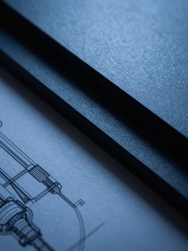 A macro shot of sharp architectural lines and high-end industrial design schematics, cool-toned directional blue light, deep navy shadows, 35mm
