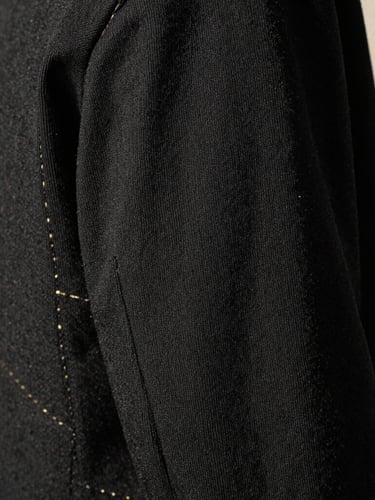Macro close-up of heavy-weight black cotton fabric texture, golden sunlight highlighting the precise stitching, minimalist studio setting, 35mm film grain