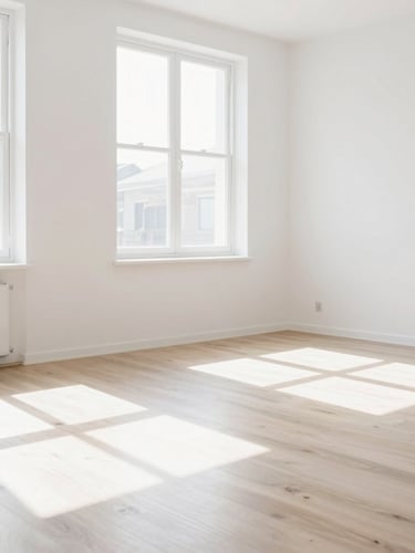 Bright high-key photography of a modern, freshly painted white living room, sunbeams streaming through a large window, spotless wooden floor, minimalist aesthetic