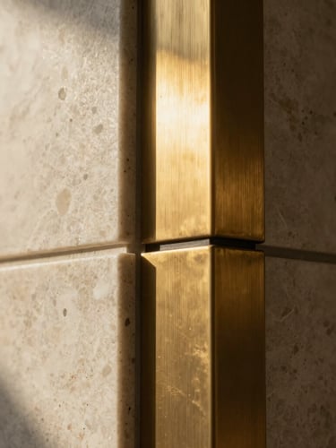 Extreme macro detail shot of a seamlessly joined honed travertine and brushed brass material intersection, dramatic low-angle sun creating deep shadows, highlighting the precision and texture. cinematic architectural photography, high-end editorial, 35mm.
