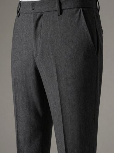 Close-up of premium men's charcoal fabric trousers drape, focusing on the sharp crease and elegant fall from waist to ankle, soft directional studio lighting, muted neutral background, 85mm lens