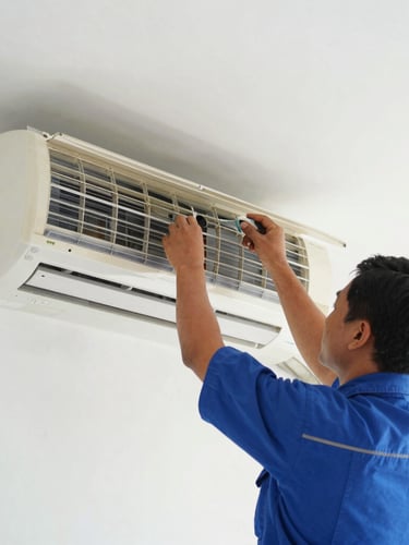 Close-up of a professional technician in blue uniform dismantling a wall-mounted AC unit inside a clean Indonesian home, bright natural daylight, 35mm lens