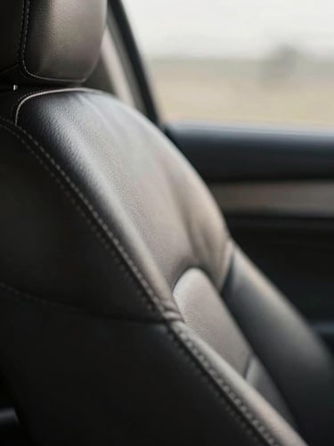 Macro detail of pristine leather stitching on an executive seat, soft morning light filtering through a tinted window, shallow depth of field.