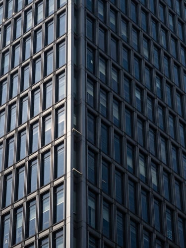 Architectural close-up of a modern steel skyscraper meeting a glass facade, dramatic high-contrast lighting, deep navy tones, crisp geometric lines, 35mm lens