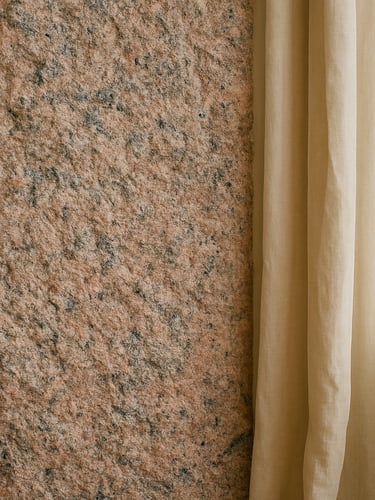 Close-up of raw pink granite wall inside a beautifully lit room, warm linen curtains, soft natural Breton daylight, medium format film
