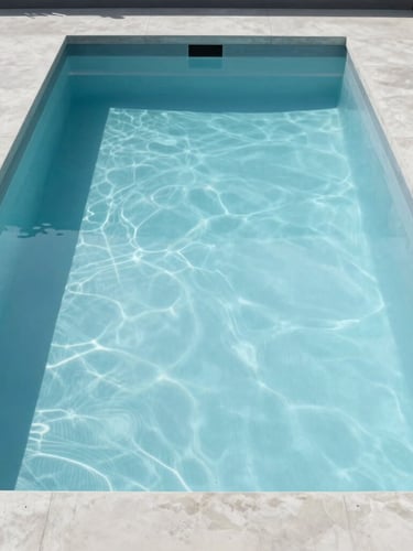 Straight-on architectural view of a minimalist concrete swimming pool with a flawless, glass-smooth light blue epoxy finish, bright natural daylight casting crisp linear shadows.