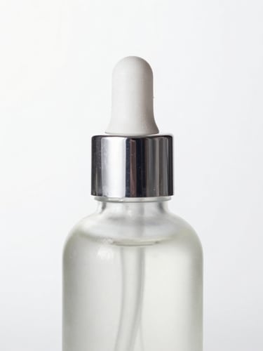 High-key product photography of a single airless glass bottle reflecting crisp studio light with soft silver reflections, clean white background, macro lens, sharp focus