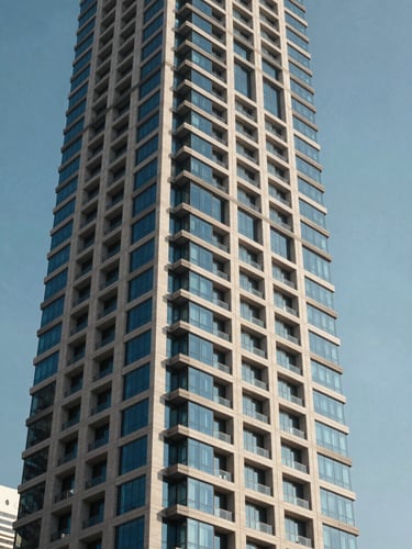 Crisp daylight architectural shot of a modern Abu Dhabi high-rise facade reflecting the blue sky, emphasizing structural integrity and clean lines