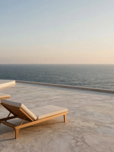 Wide-angle architectural photograph of a travertine terrace meeting the open ocean at golden hour, minimalist outdoor lounge chairs, soft warm light.