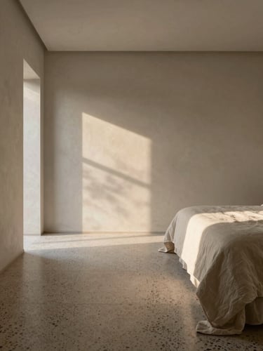 One-point perspective of a minimalist bedroom at sunrise, soft morning light casting long shadows on terrazzo floors, raw plaster walls, linen bedding.