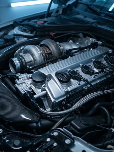 Close-up of a clean modern engine bay, cool blue workshop lighting, sharp metallic reflections on the cylinder head, 50mm lens