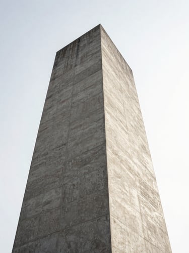 Low-angle architectural shot of a monolithic concrete tower against a stark white sky, casting sharp geometric shadows.