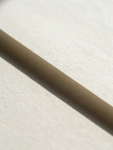 Macro close-up of heavy-weight cotton paper document with sharp geometric shadow cast across the page