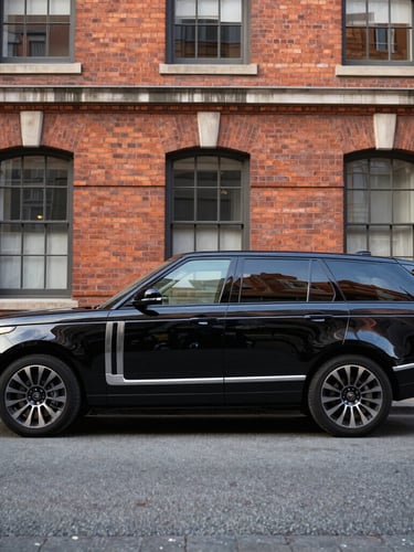 Immaculate black executive transport SUV parked in front of a historic brick building, soft early morning light, reflections on polished metal, sharp focus, 35mm