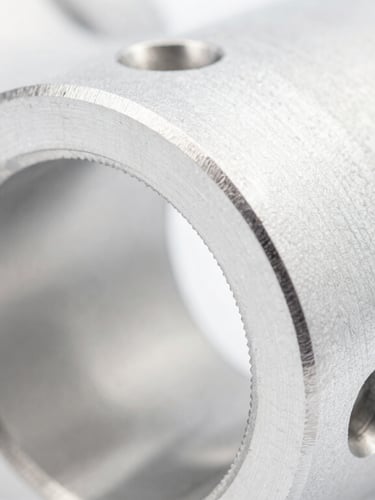 Macro close-up of a pristine machined aluminum aerospace component with complex drill holes, sharp metallic edges, bright high-key lighting, shallow depth of field.