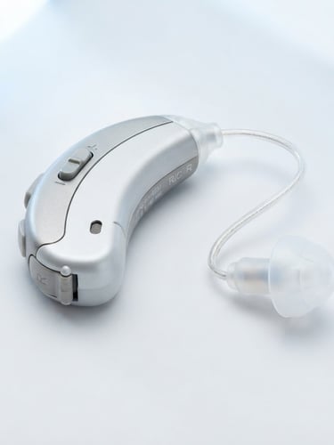 Macro close-up of a sleek rechargeable RIC hearing aid, bright high-key studio lighting, soft blue and white tones, sharp focus, 85mm