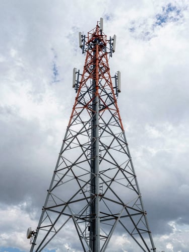 Wide-angle portrait of a massive steel telecommunications tower rising against a dramatic overcast Andean sky, clean industrial composition