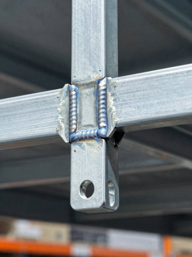 Macro shot of a clean powder-coated steel shelf bracket connection, high-contrast commercial showroom lighting, sharp focus on structural weld