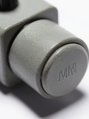 Macro extreme close-up of a physical gray industrial microswitch button, harsh direct office lighting, sharp shadows, technical orthographic view, desaturated industrial tones, 35mm
