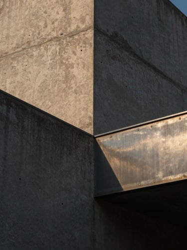 Close-up of raw textured concrete and brushed steel materials, dramatic low-sun casting long shadows, sharp architectural framing