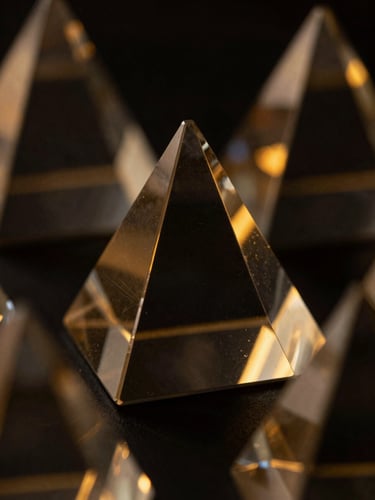 Macro close-up of dark glass geometric prisms reflecting warm gold ambient light, sharp refraction lines, dark editorial tech style