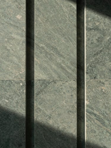 Tactile close-up of a sleek travertine marble entryway with soft diffused morning light, architectural symmetry, 35mm