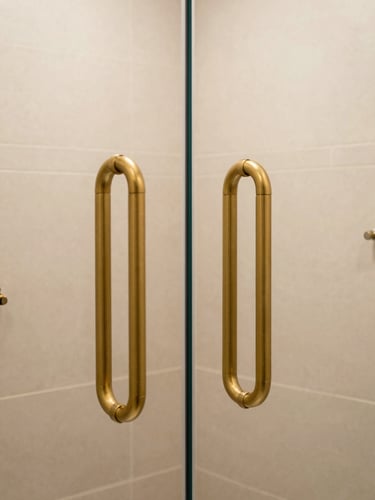 Warm editorial photography of an elegant walk-in shower with matte gold grab bars, natural daylight, beige tiles, and high-contrast details, 35mm