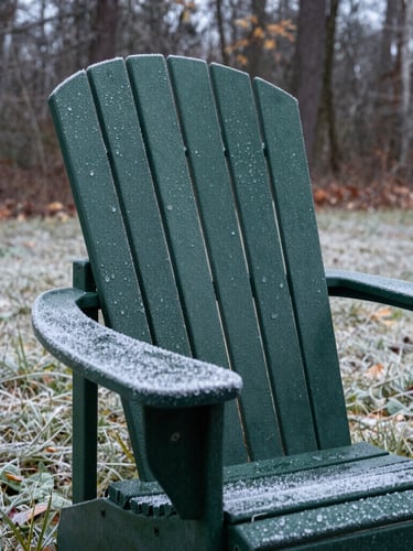 Close-up of a deep forest green Adirondack chair on a frost-covered lawn during a crisp autumn morning, showing morning dew beads on the thick textured resin surface, 35mm lens.